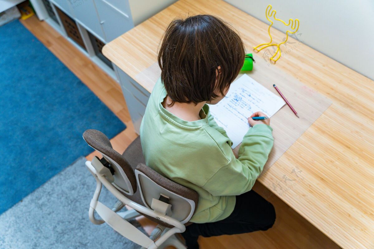 年轻小男孩坐在桌子旁做作业家集中儿童写作练习很高兴在家上学概念童年房间专注