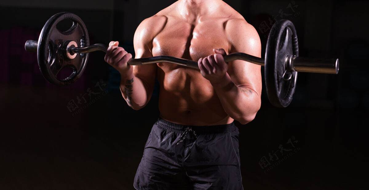 肌肉健美运动员做运动的特写镜头杠铃强壮在黑暗中裸露躯干的男性杠铃哑铃完美