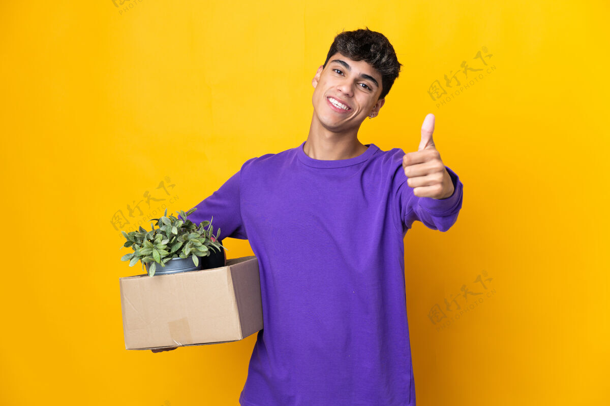 堆栈一个男人一边移动一边竖起大拇指捡起装满东西的箱子 因为发生了好事包装房子微笑