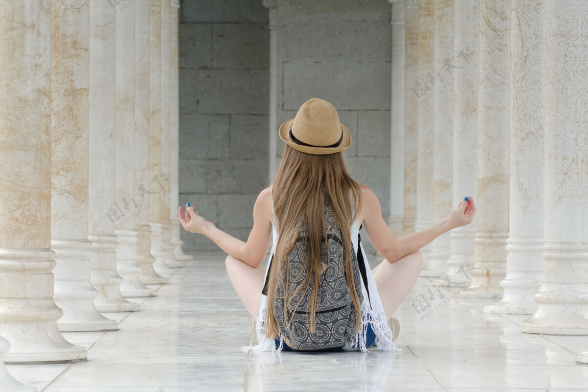 拱廊一个戴着帽子 背着背包的女人坐在莲花柱中间旅行旅行后方