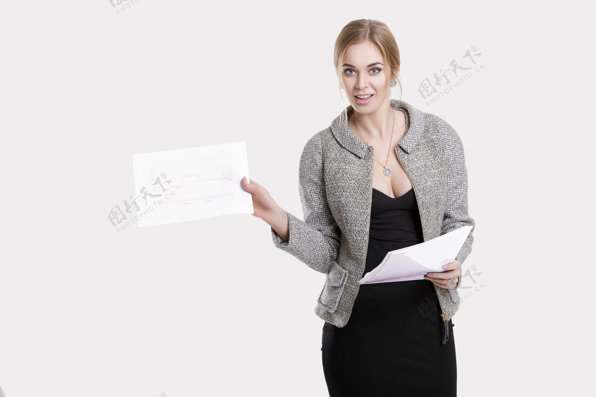 性感年轻漂亮的女商人 金发碧眼 穿着黑色连衣裙 夹克夹着一堆文件 在灰色的背景下微笑着工人服装女商人