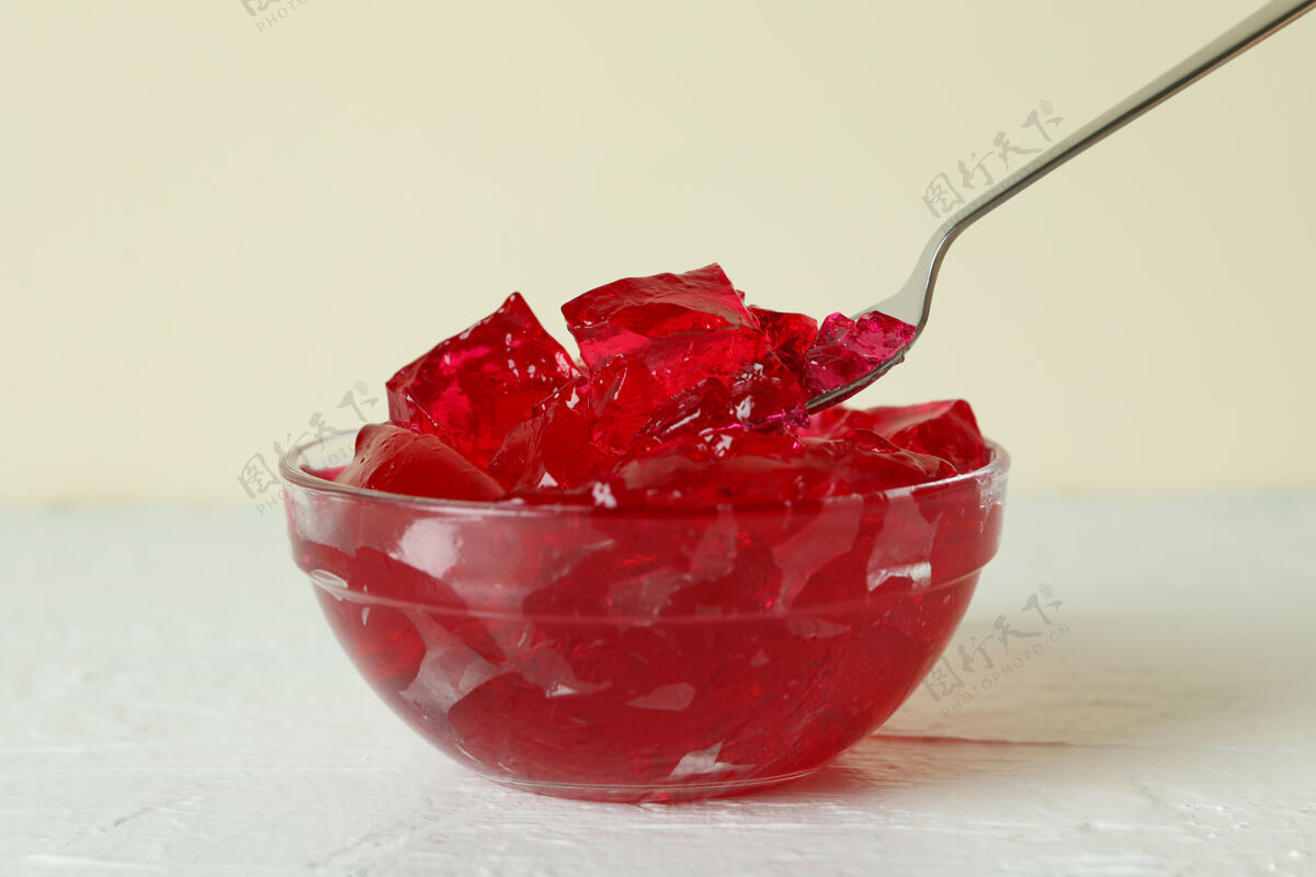 食物一碗草莓果冻和勺子放在白色纹理的桌子上美味水果甜味
