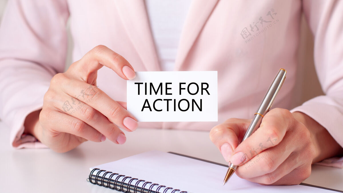 笔一个女人用一支银色的钢笔和一张写着“行动时间”的手持式卡片写在笔记本上商业和教育理念客户会计卡片