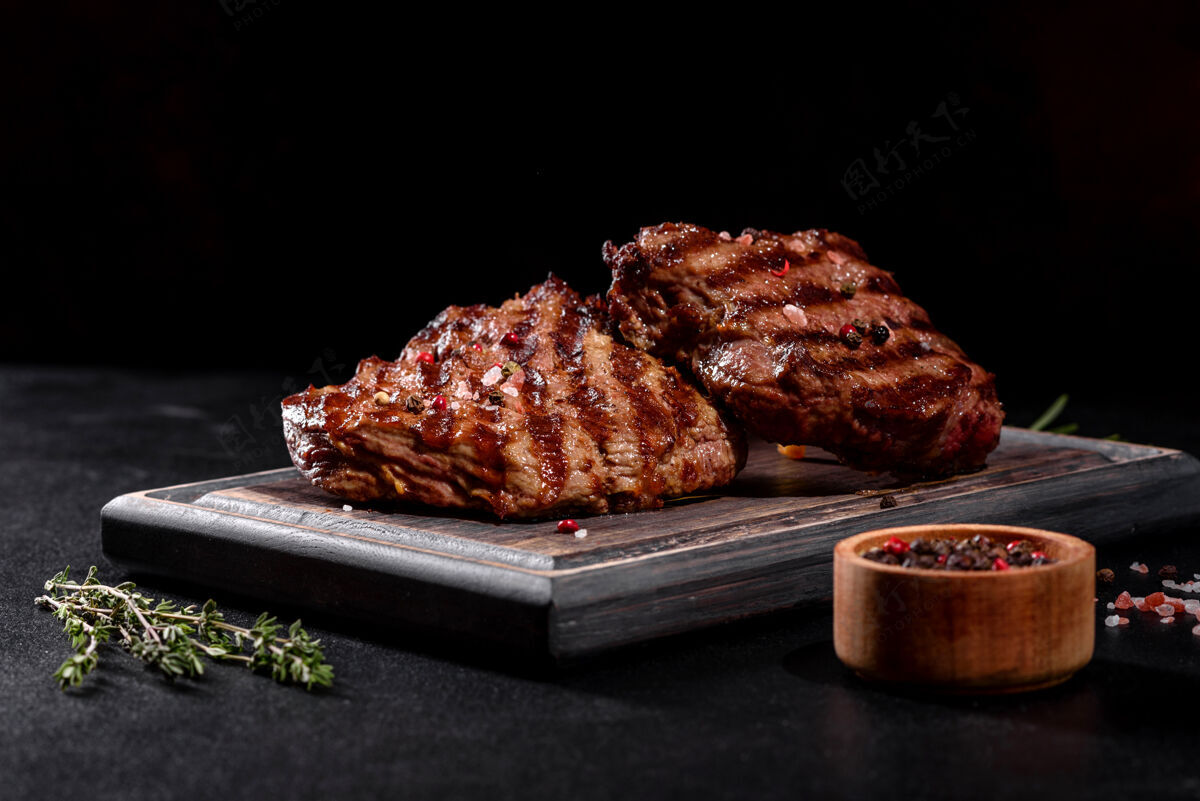 木头新鲜多汁美味的牛排 放在深色烤箱里背景.肉用香料和香草做的菜板特写牛排
