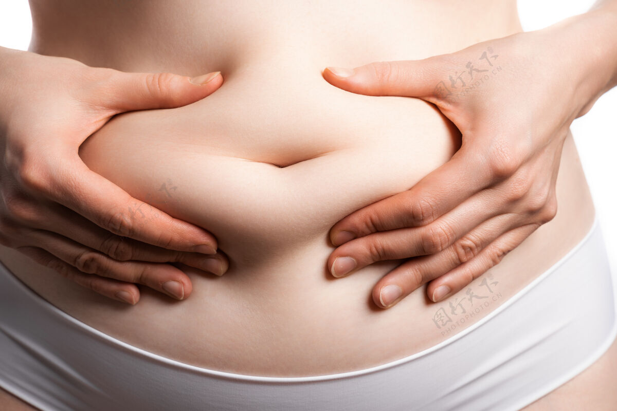 腹部一张女性腹部的近景照片 她在肚脐上捏了一小层脂肪年轻护理健康