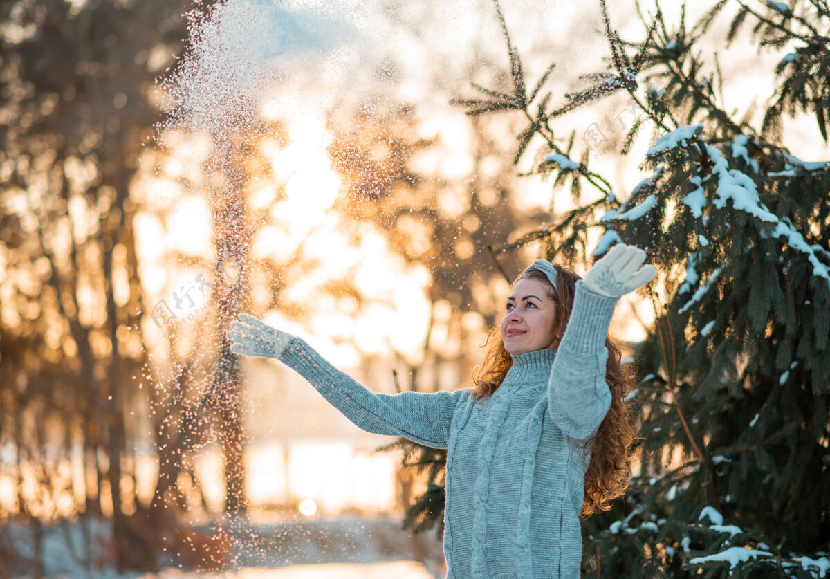 毛衣快乐美丽的年轻女子穿着灰色温暖的毛衣吹雪花从她的手在冬天的一天姿势模型雪