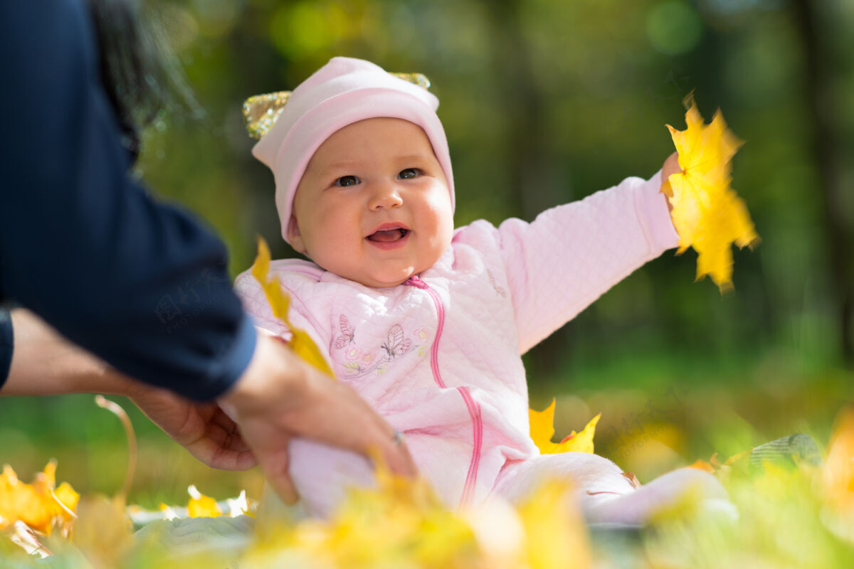 天真笑着的女婴在公园里和妈妈玩秋叶 低角度的画像人草地托儿所