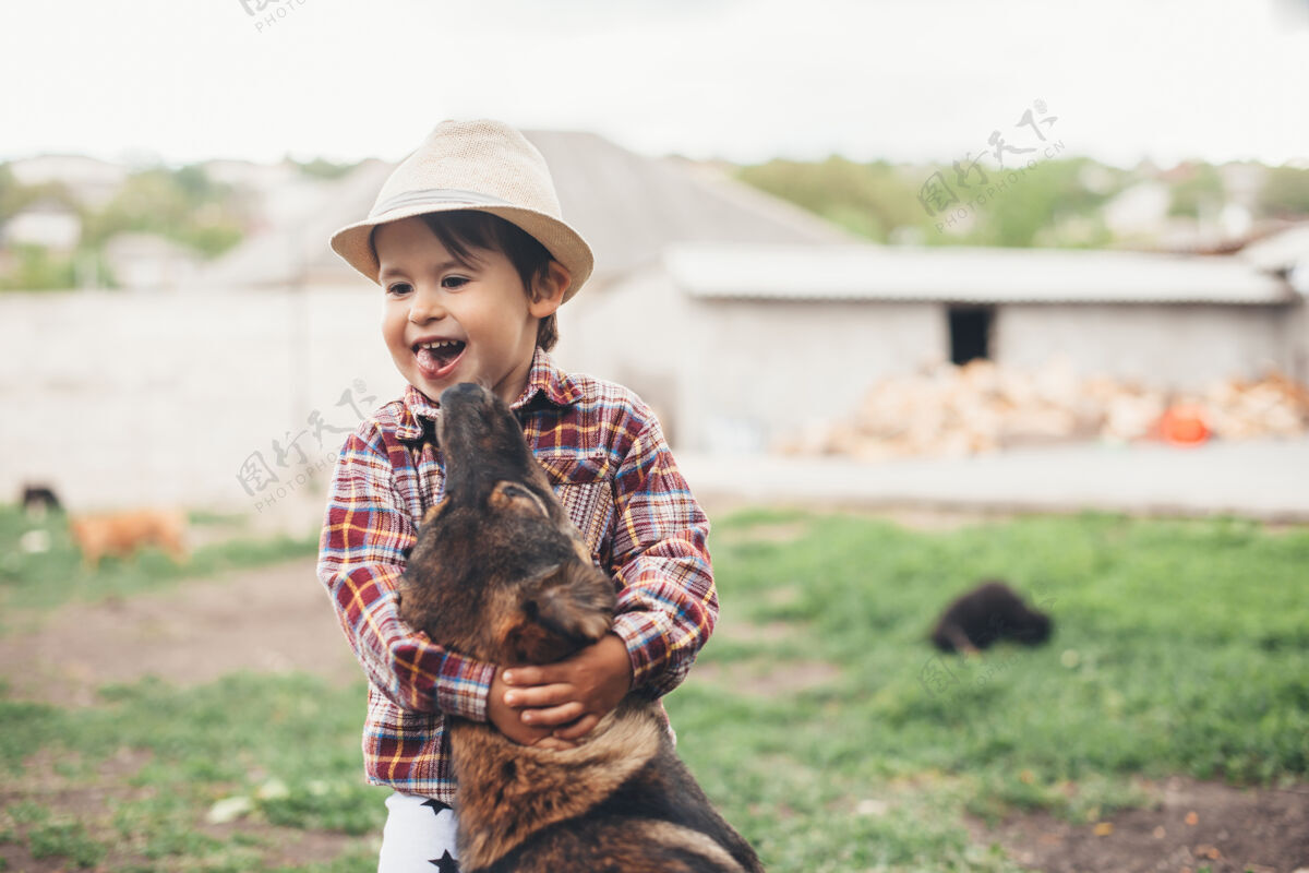 哺乳动物年轻的白人男孩头戴帽子在外面玩他的狗拥抱他魅力生活方式休闲