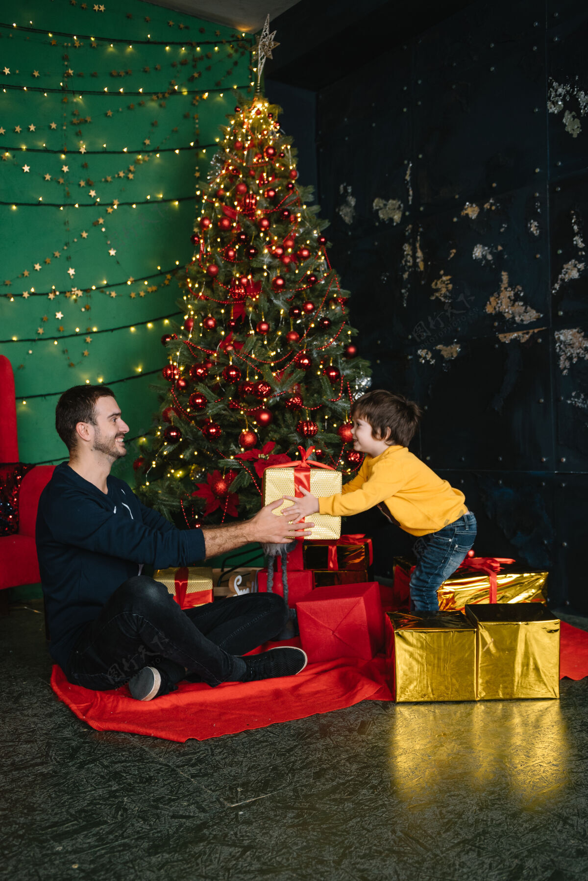 微笑年轻漂亮的父亲带着可爱的儿子在圣诞树旁礼物快乐圣诞节礼物家庭快乐