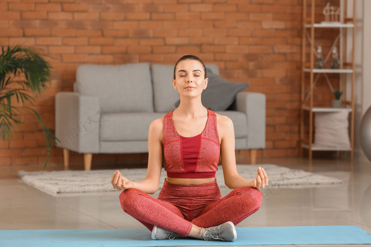 成人运动型年轻女子在家练习瑜伽护理坐着放松