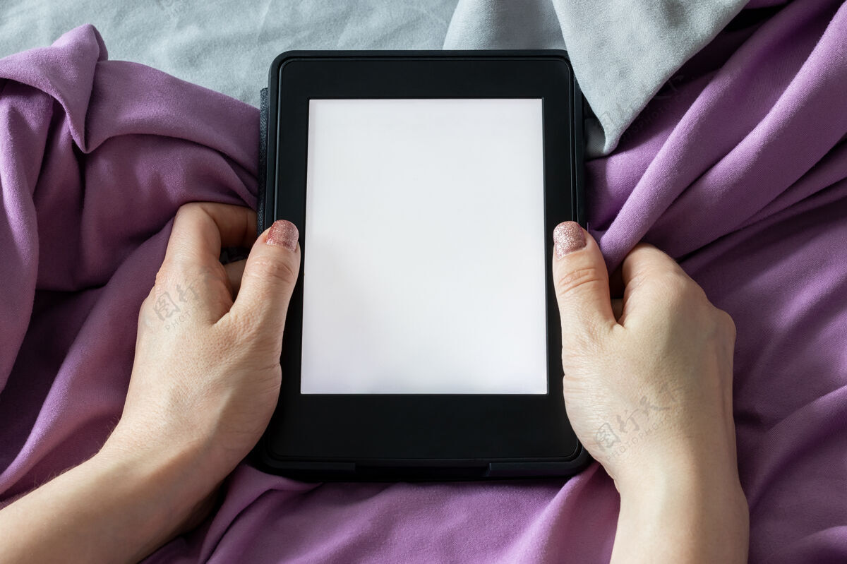 教育一本现代的黑色电子阅读器电子书 在一个空白的屏幕上 女性手里拿着一本灰紫色的床模型超细纤维床上用品特写卧室设备显示器