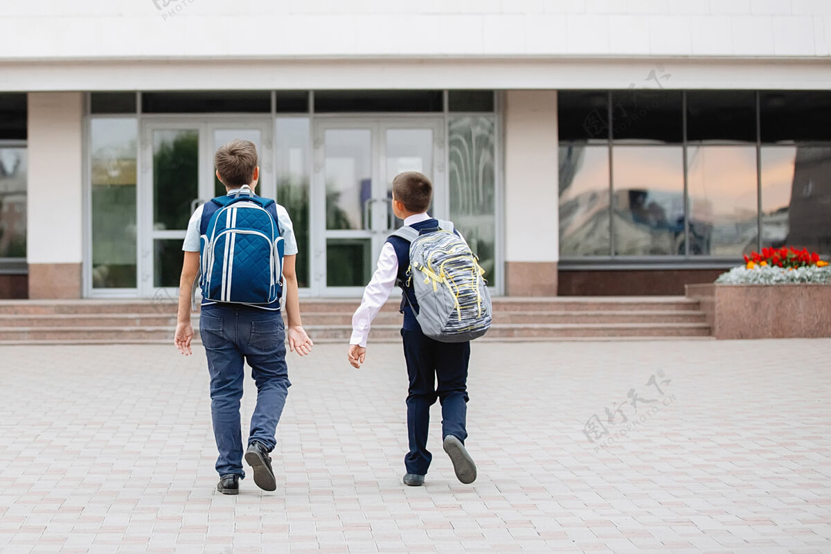 跑步两个穿着校服背着背包的青少年去上学户外教育制服