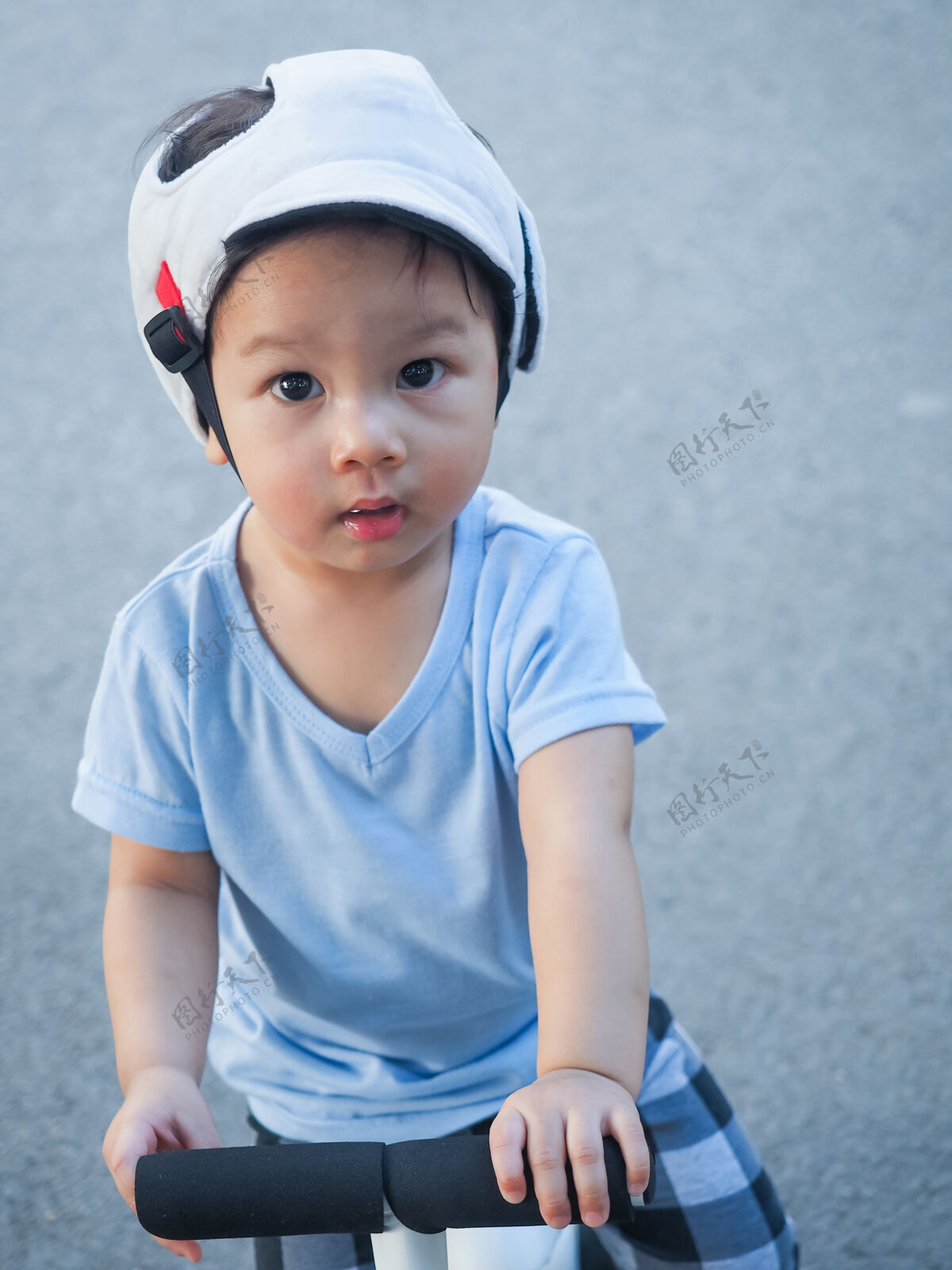 小可爱的亚洲小男孩戴着安全帽 头戴护盾 在路上学习骑他的第一辆白色跑步自行车脸童年乐趣
