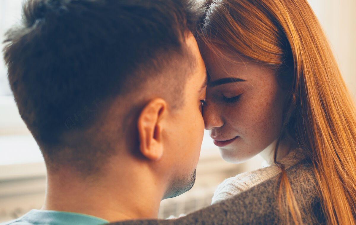性感一位红发雀斑美女和她的男人面对面坐在一起 闭上眼睛 然后在家里接吻年轻感情亲吻