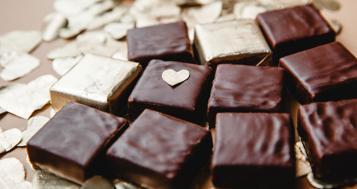 美味正方形的黑巧克力糖果和铝箔切心特写在桌子上锡纸巧克力甜点