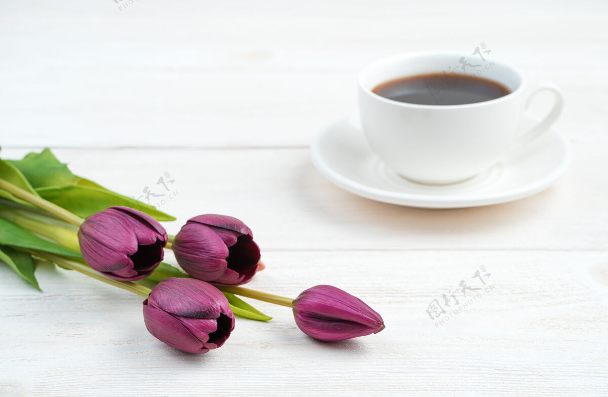 花束紫色的花和一个白色的咖啡杯在一个浅色的木制背景上咖啡饮料杯子