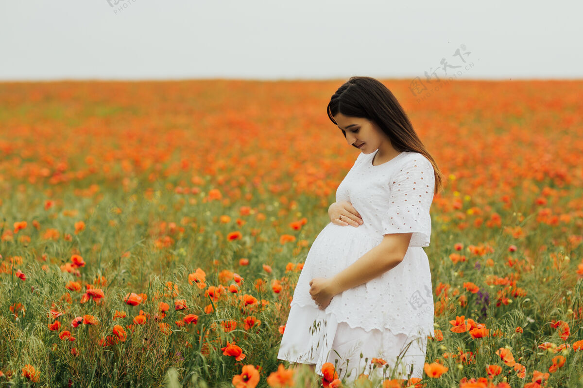 乡村美丽的孕妇在户外罂粟田自然罂粟花放松