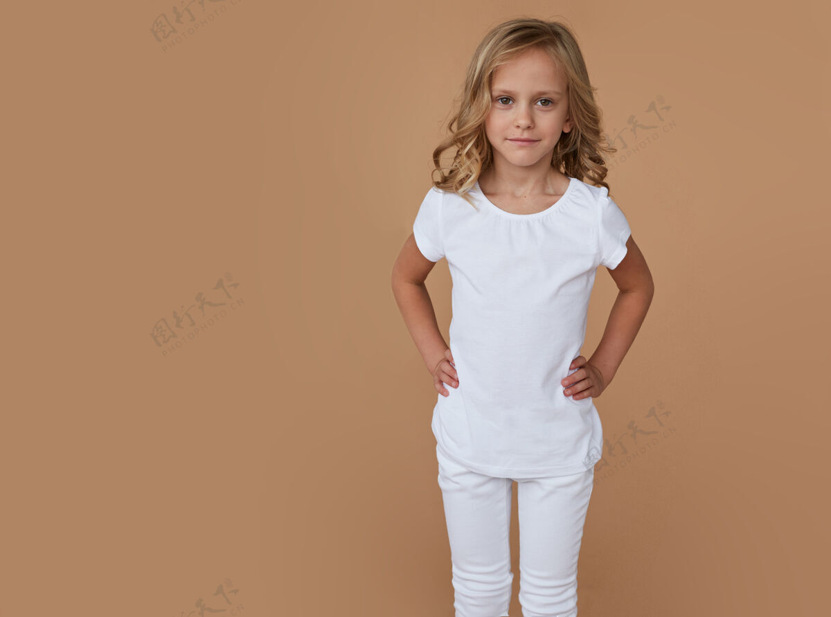 快乐一头卷发 穿着白色衣服的漂亮小女孩的正面肖像童年姿势时尚