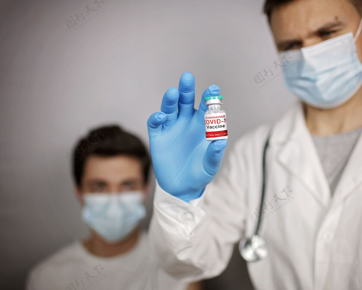 治疗医生戴着医用口罩和手套 拿着装有冠状病毒疫苗的安瓿和注射器剂量安瓿疫苗