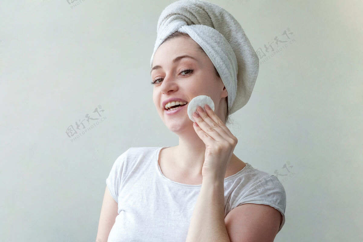 触摸头上戴着毛巾的微笑女人的美丽肖像 柔软健康的皮肤 用隔离在白色背景上的化妆棉卸妆敏感感官Maquillage