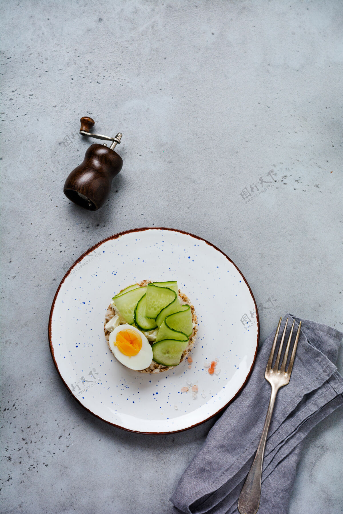 餐厅用煮鸡蛋和黄瓜夹在灰色旧面上的陶瓷板上三明治胡椒小吃