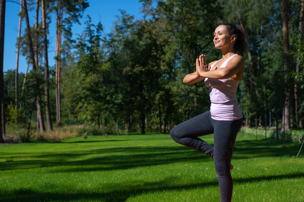 姿势美丽的女人做体位法户外瑜伽平衡树体位法锻炼瑜伽健身