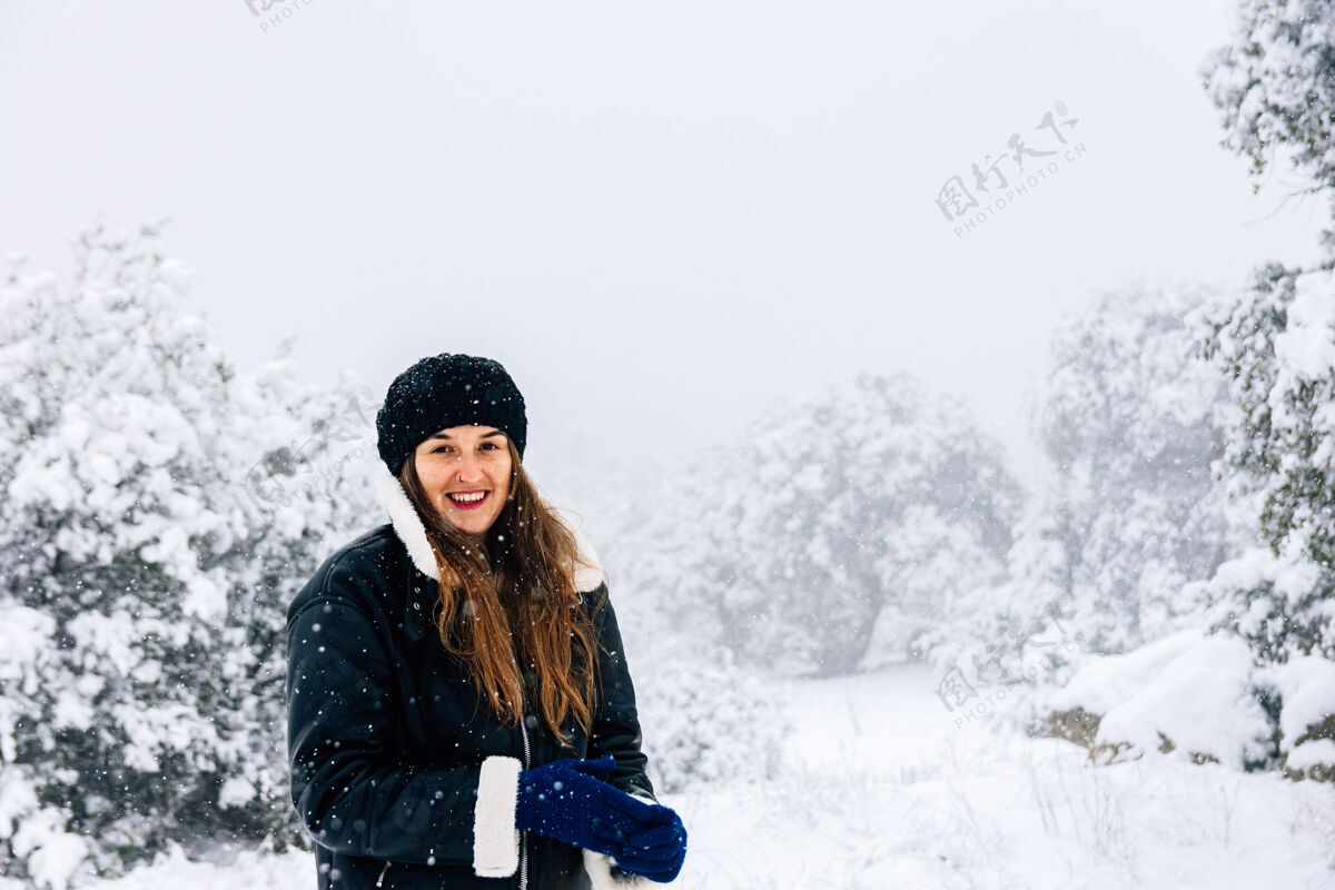 穿上一个美丽的女人在下雪时用手机拍照的画像凉爽金发孤独