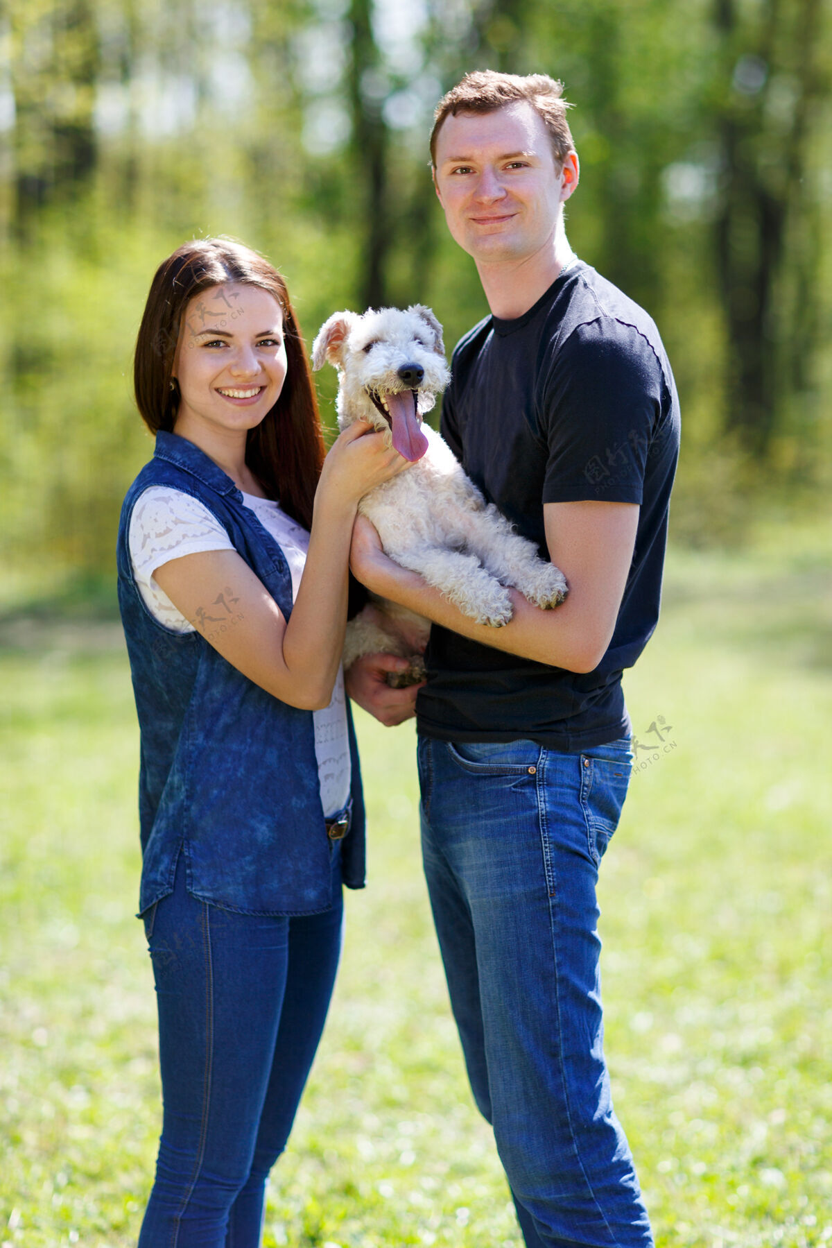 女人快乐的年轻夫妇和他们的狗在公园里微笑外面男性