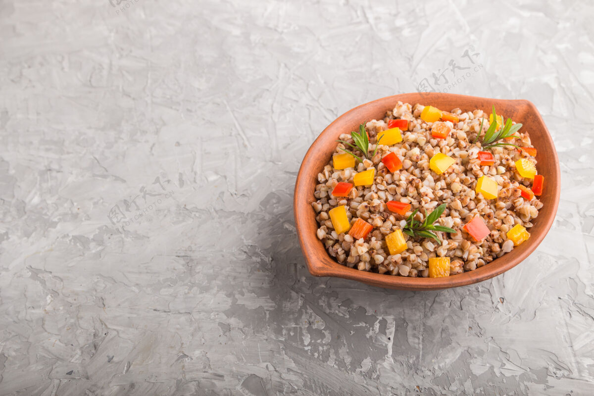 烹饪荞麦粥和蔬菜在一个灰色的混凝土表面粘土碗侧视图 复制空间热烹饪混凝土