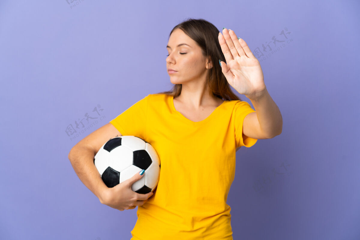 女子年轻的立陶宛足球运动员女子孤立在紫色的背景下做出停止的手势和失望限制青年严肃