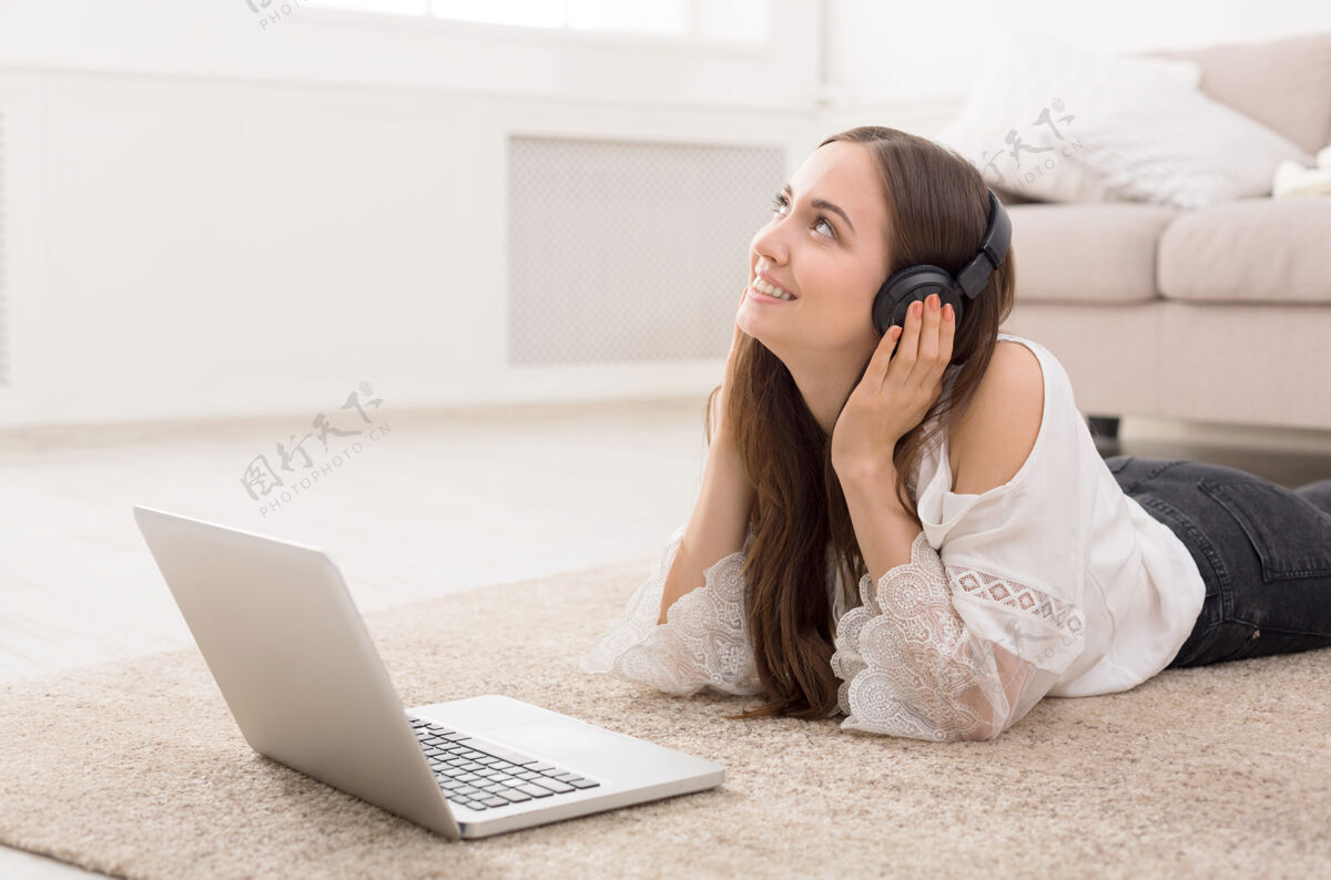 音乐戴着耳机的年轻女子在笔记本电脑上上网学习笔记本电脑快乐