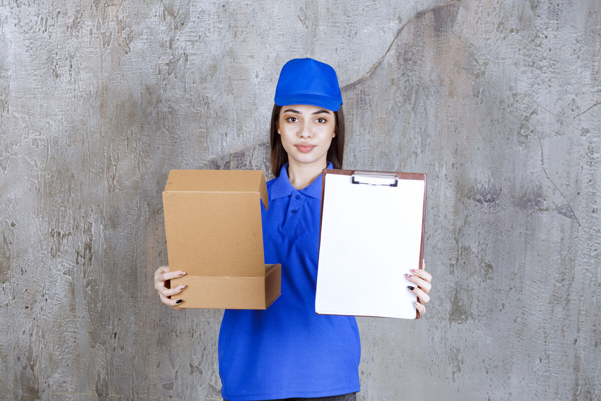 产品身着蓝色制服的女服务人员手持一个打开的纸板箱 出示签名清单服装女售货员快递