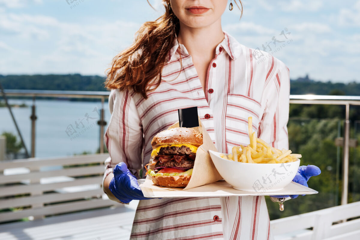 服务烧烤餐厅红发女子戴着蓝色手套和条纹衬衫在烧烤餐厅约会露台咖啡馆衬衫