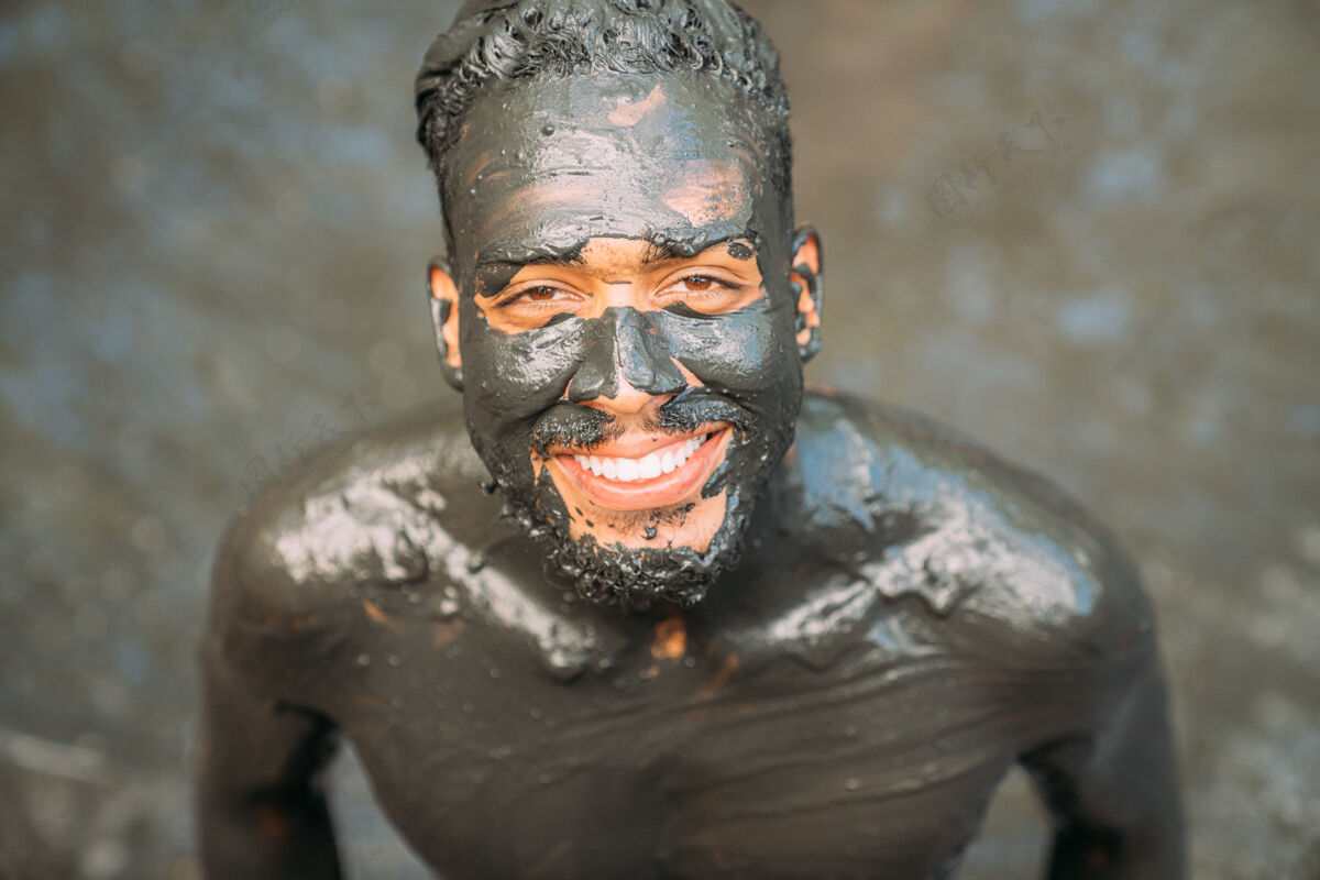 水微笑的拉丁美洲年轻人正在做绿泥治疗粘土皮肤护理环境