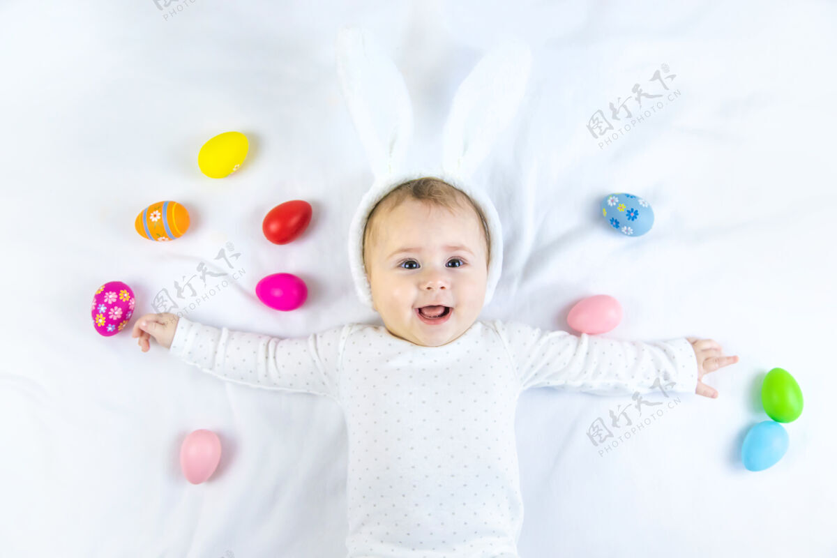 幼儿宝宝穿得像兔子 在白色的表面上放复活节彩蛋小有趣多彩