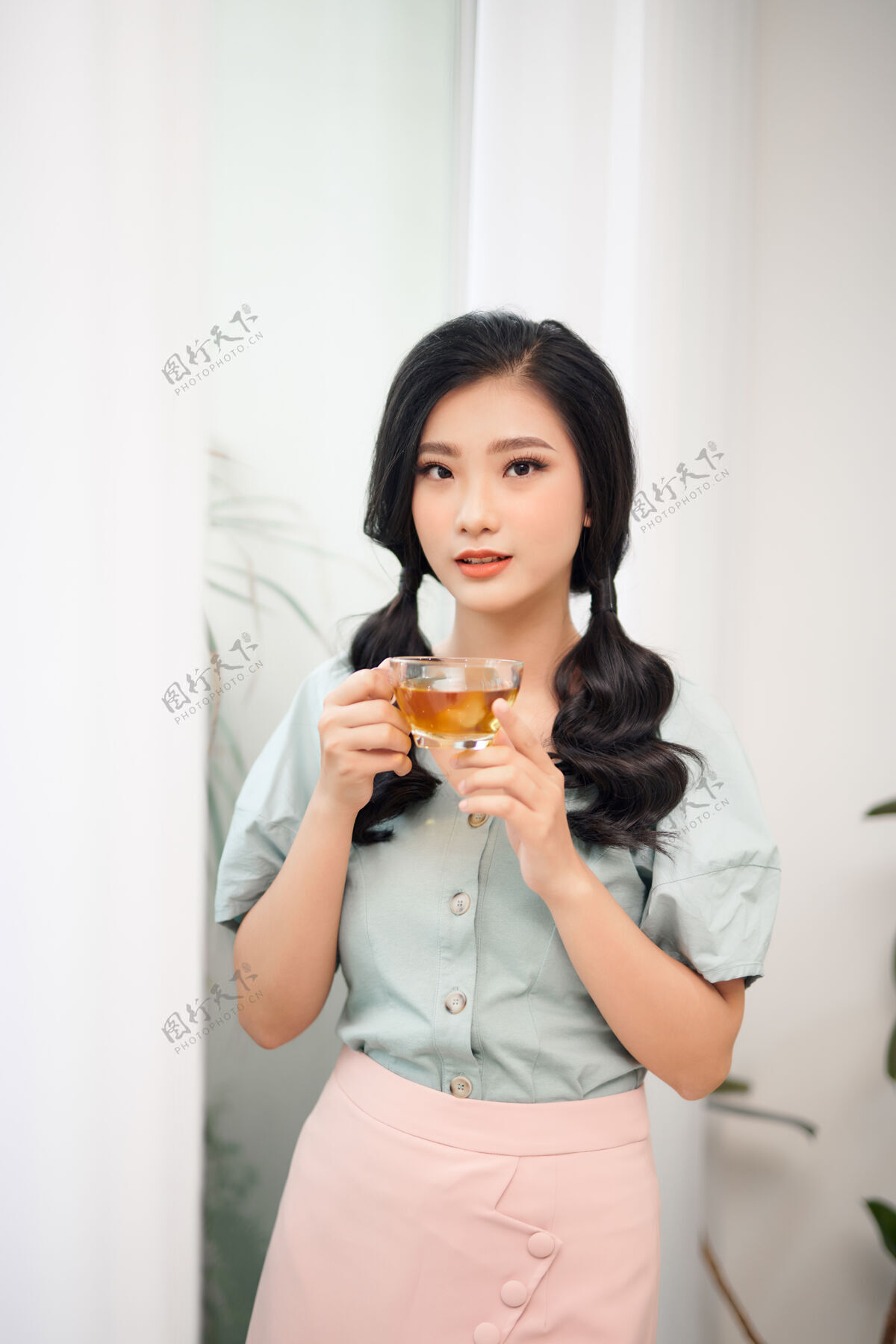 20岁美丽的女人在用杯子喝茶休息窗户女士