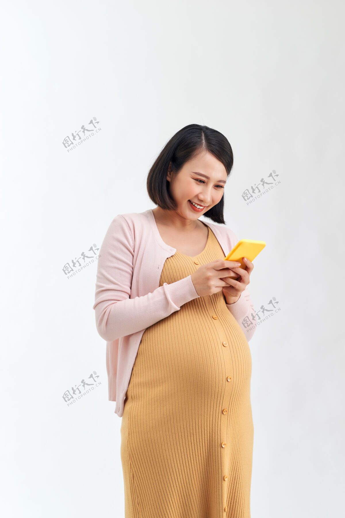 女人一个微笑可爱的孕妇肖像使用手机隔离在白色背景上怀孕怀孕韩国