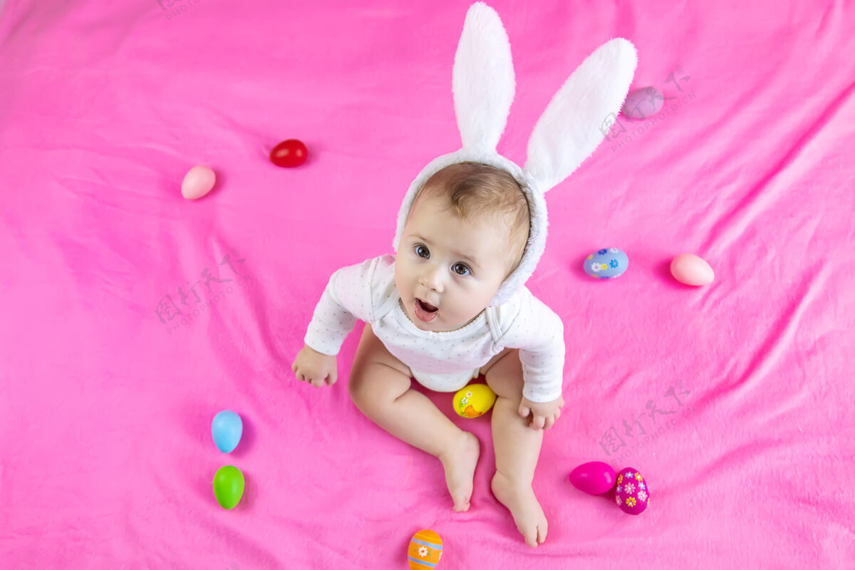 玩耍穿得像兔子的宝宝 带着复活节彩蛋过复活节微笑脸肖像