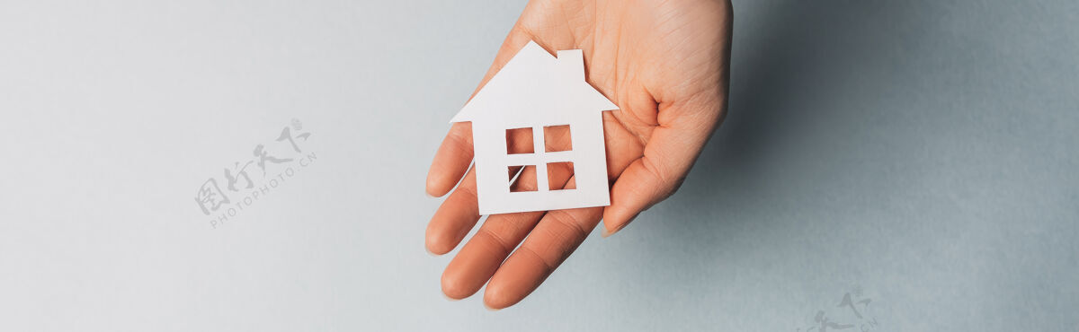 形状一个女人拿着一个纸房子 她的手和太阳放在淡蓝色的空间里租金女人房地产