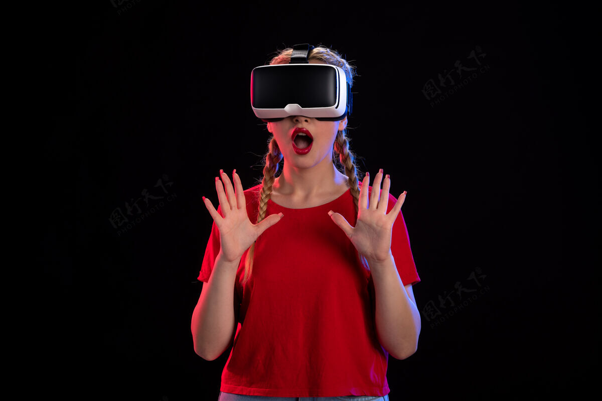 头盔年轻女性在黑暗视觉超声上玩虚拟现实的前视图视觉年轻女性游戏