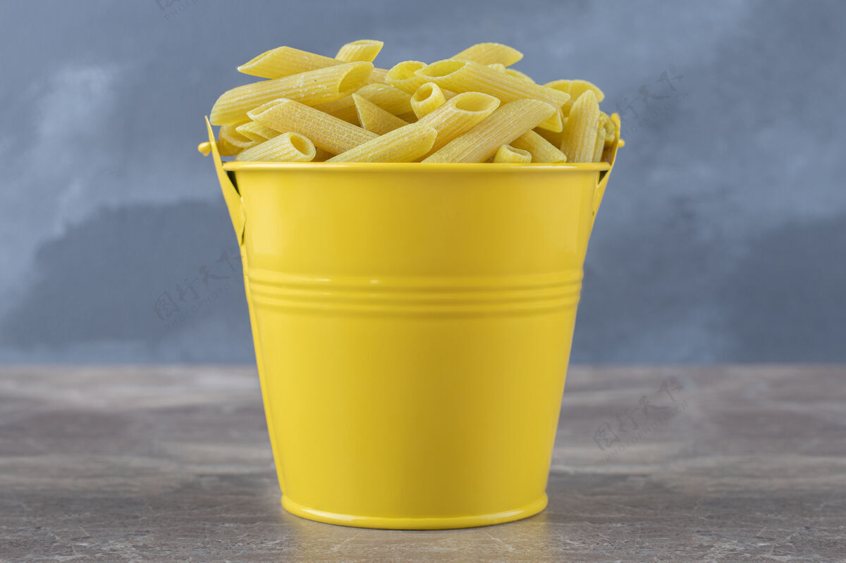 美味黄色桶里的意大利面 放在大理石表面上美味桶装风味