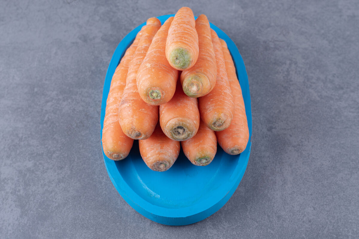 营养蓝色托盘上的一堆胡萝卜 大理石表面上的胡萝卜好吃的好吃
