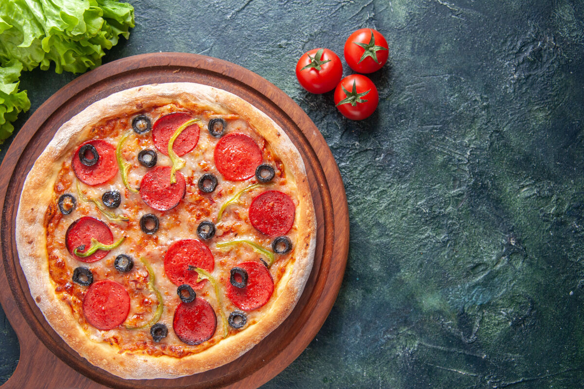 橄榄美味的自制披萨在木制砧板上番茄酱绿色的番茄酱包在黑暗的表面晚餐午餐美味