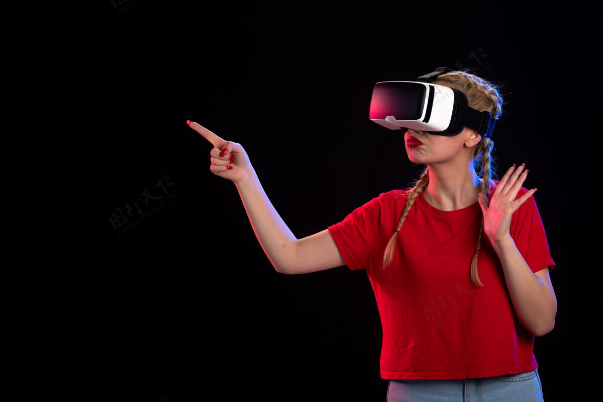 年轻女性年轻女性在黑暗游戏技术上玩虚拟现实的正面视图超声波视觉科技漂亮姿势