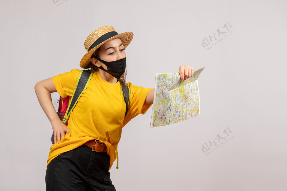 面具正面图年轻的旅行者背着背包看地图 手放在腰上面罩年轻旅行者手