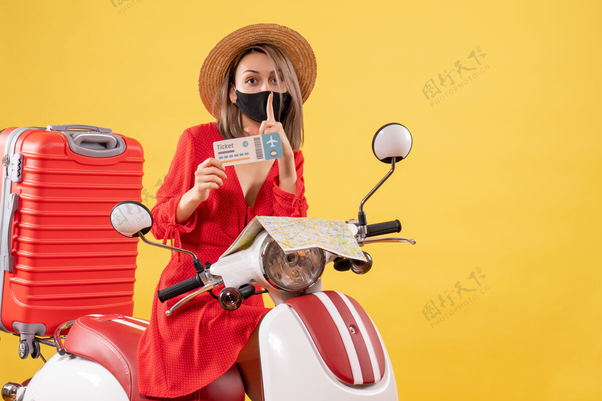 流行正面图：戴着黑色面罩的年轻女士 手持制票安静标志举行旅游假期