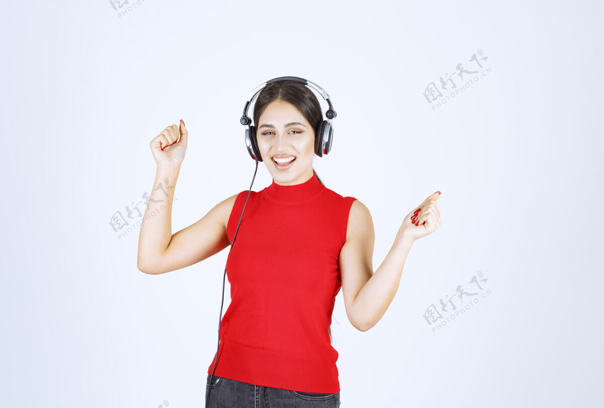 年轻穿着红衬衫的Dj戴着耳机欣赏音乐乐趣模特姿势