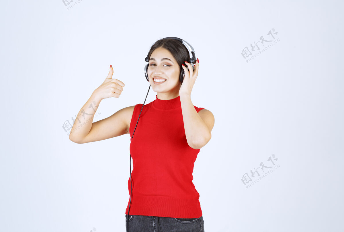 年轻穿着红衬衫的Dj戴着耳机欣赏音乐女性满意工人