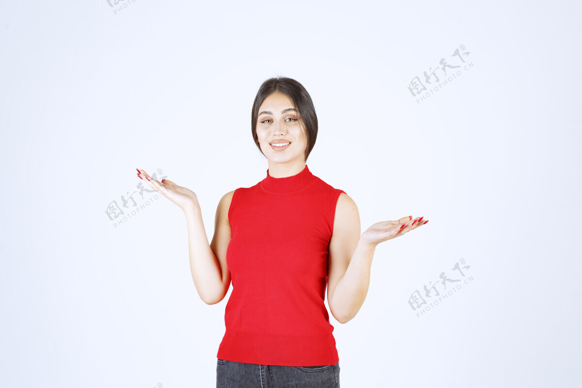 姿势穿红衬衫的女孩在她张开的手上展示着什么人成人女售货员