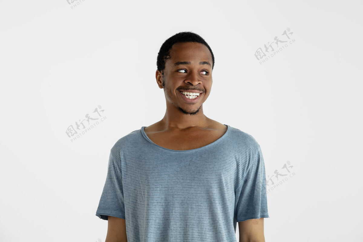 非洲美丽的男性半身像隔离在白色的墙上年轻情绪化的非洲裔美国人在蓝色衬衫面部表情 人类的情感 广告概念微笑 看着身边胡须肖像广告